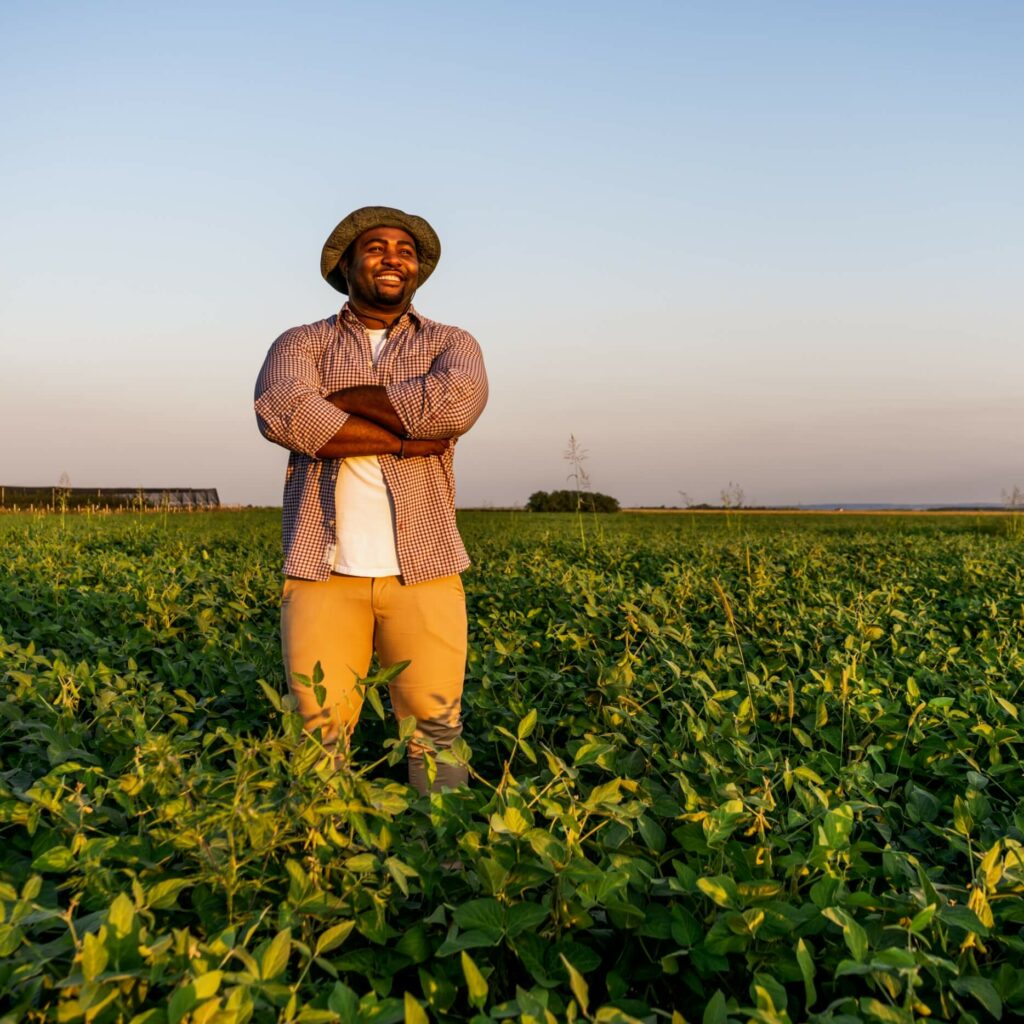 young person of color standing in a field of soybeans
